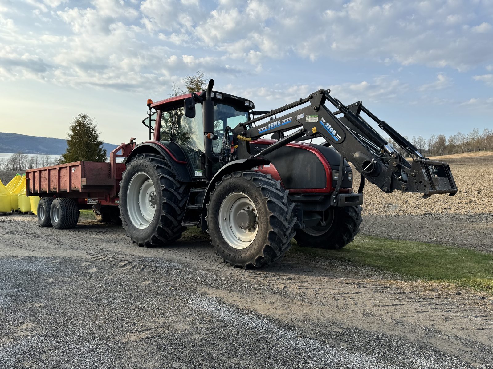Traktor med frontlaster og henger på plassen ved verkstedet