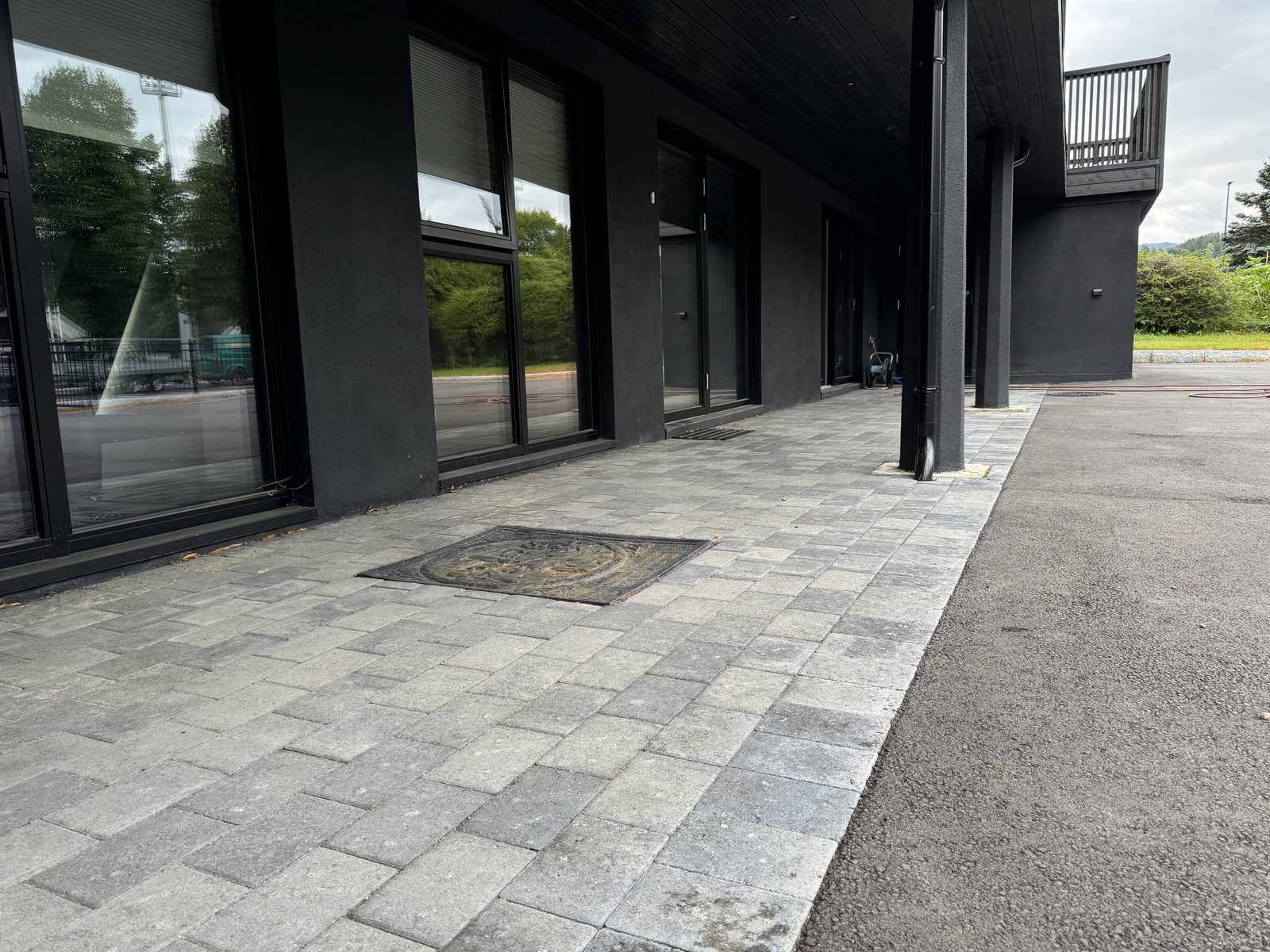 Belegningsstein foran moderne bygg med store vinduer